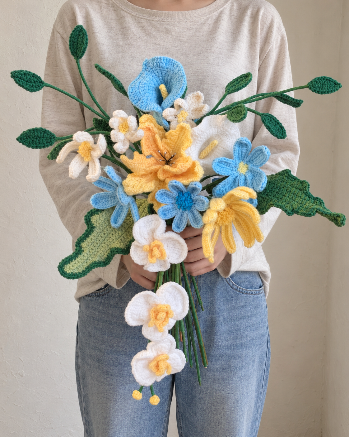 Blue, yellow and white handmade crochet flower bouquet held by a model